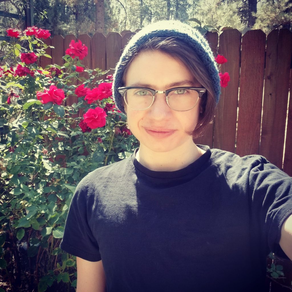 James Jasper Grimm smiling in front of rose bushes on a sunny day